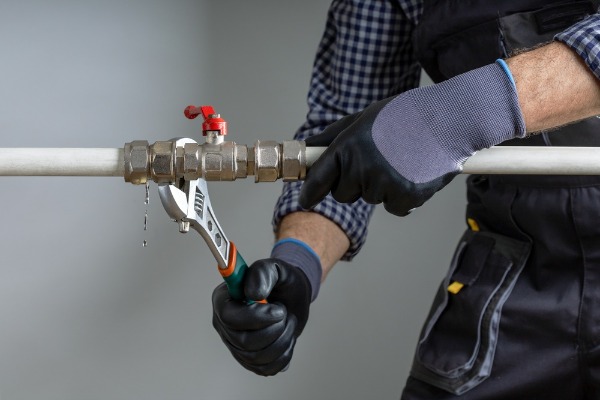 plumber fixing leaking pipe valve with wrench